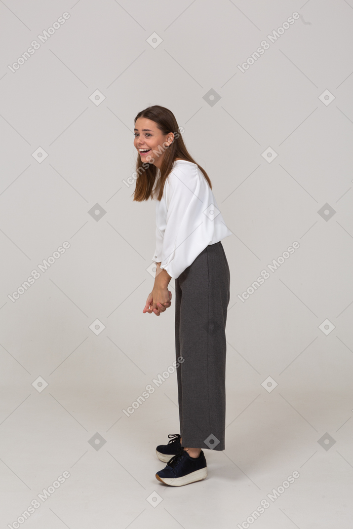 一位身着办公室服装、前倾的笑着的年轻女士的侧视图