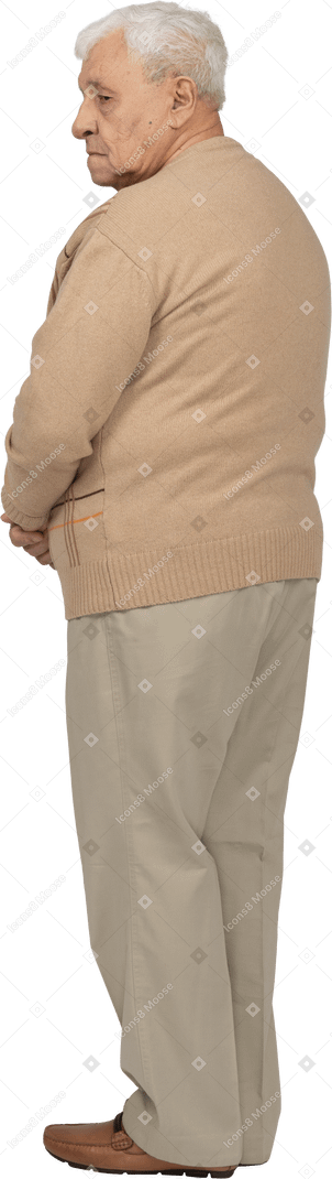 じっと立っているカジュアルな服装の老人の背面図
