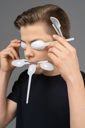 Portrait d'un homme faisant un masque de cuillères en plastique