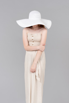 Teenage girl wearing white hat which closing her face