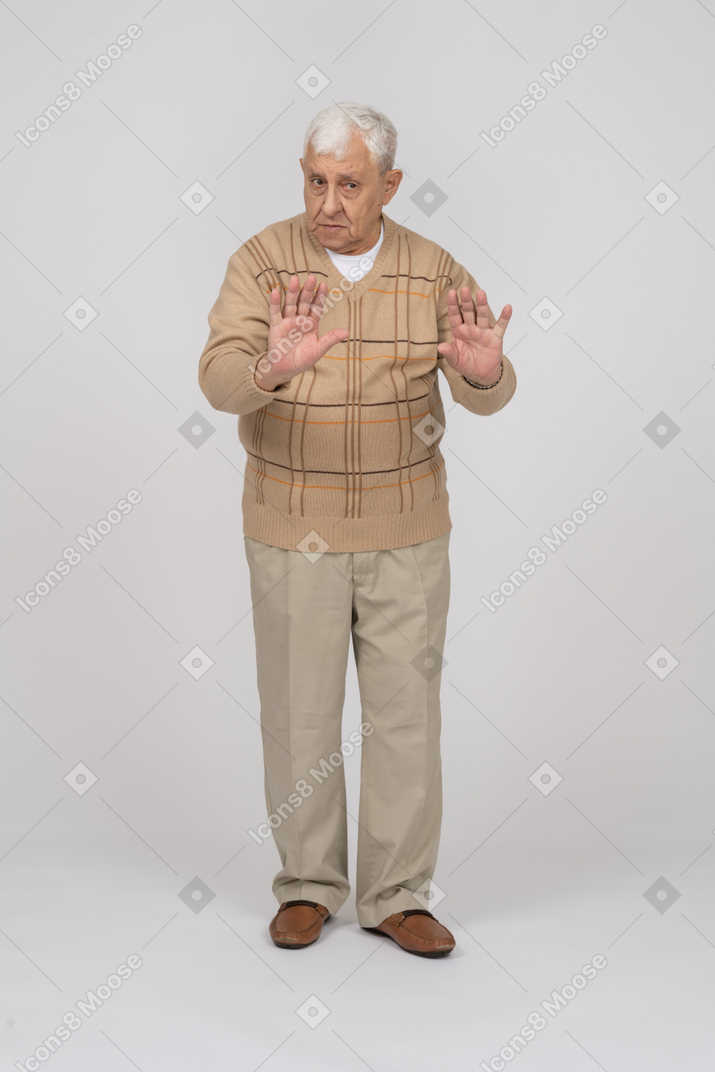 Vista frontal de um velho em roupas casuais, mostrando o gesto de parada