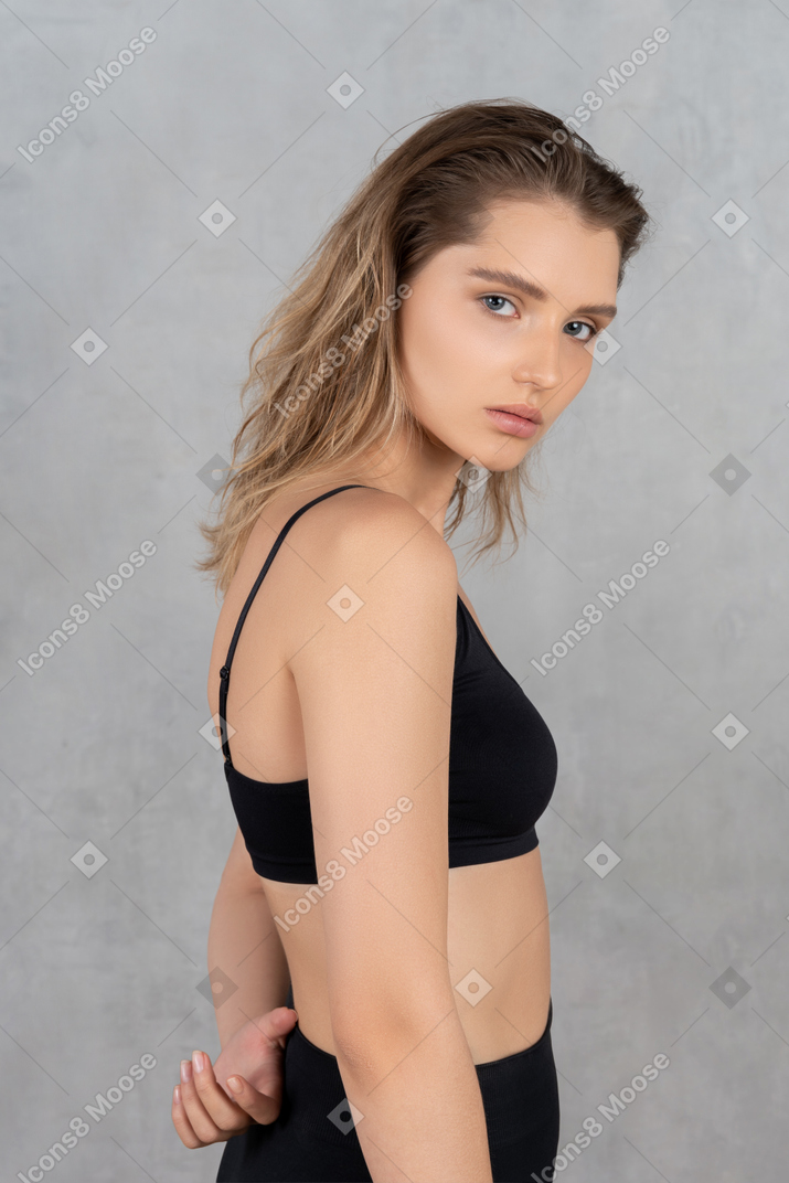 Side view of young woman posing with hand behind her back