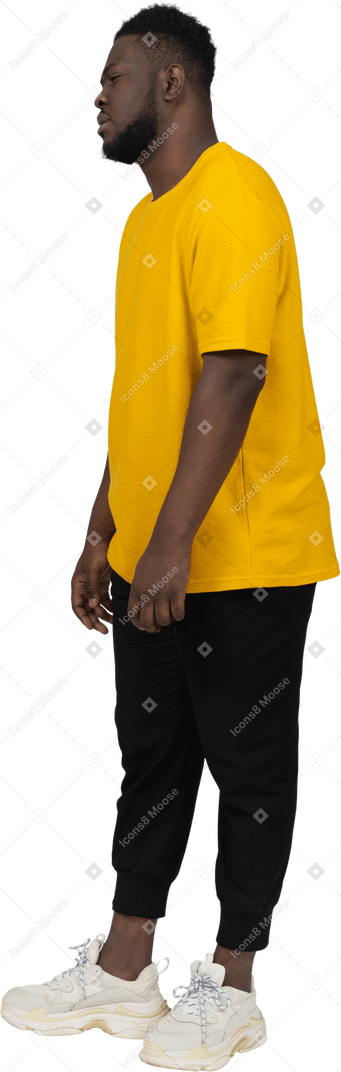 노란색 티셔츠를 입은 피곤하고 내키지 않는 젊은 검은 피부 남자의 4분의 3 보기