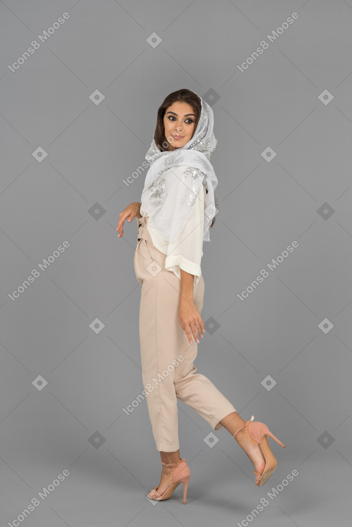 Serious young woman in headscarf looking back