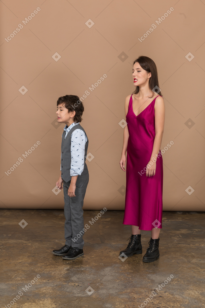 Вид сбоку молодой женщины в красном платье и мальчика