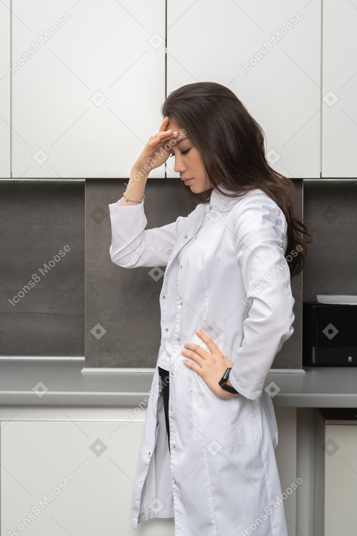 Close-up una enfermera pensativa tocando su cabeza