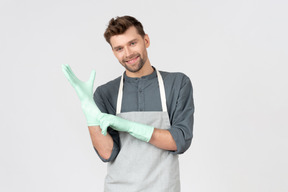 Young guy wearing apron and putting on gloves