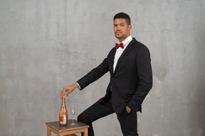 シャンパンのボトルとグラスの隣に立っている男性