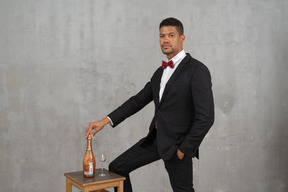 Homme debout à côté d'une bouteille de champagne et d'un verre