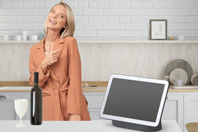 A woman is standing in front of a kitchen counter with a tablet computer