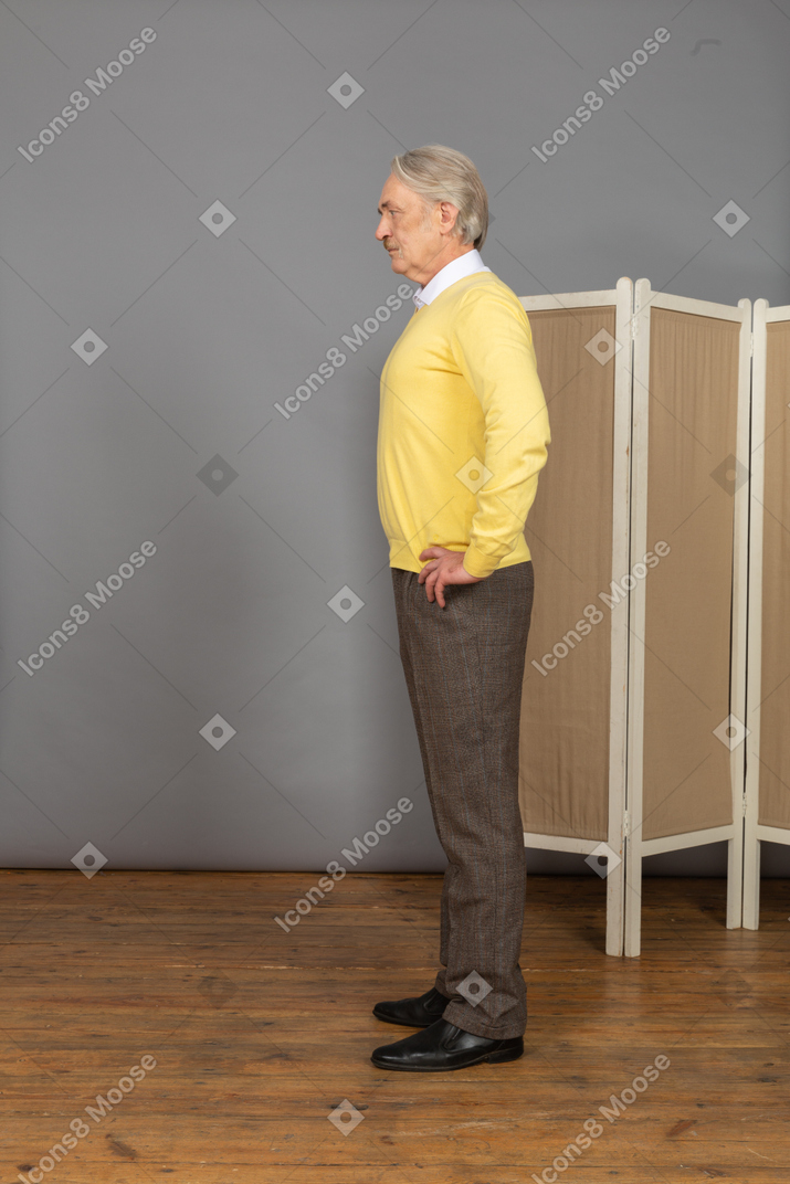 Vue latérale d'un vieil homme sérieux mettant les mains sur les hanches