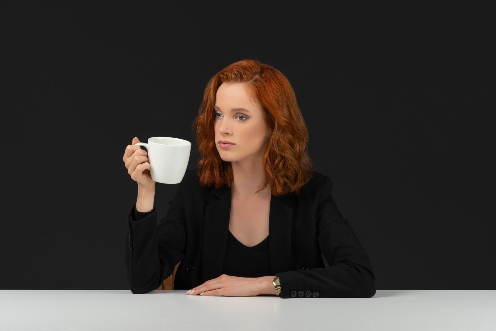 Good looking young woman dressed in black and drinking coffee