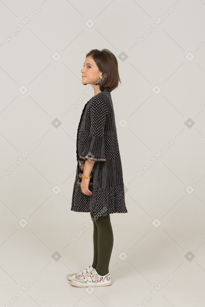 Side view of a cheerful little girl in dress looking aside