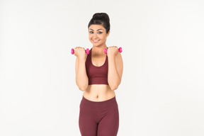 Young indian woman in sportswear holding hand weights