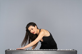 Front view of a young lady in black dress putting her hand on keyboard