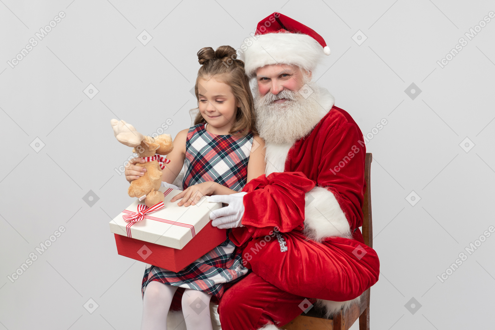 Kid girl sitting on santa's knees and holding deer stuffed toy