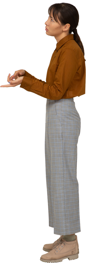 Vista laterale di una giovane donna asiatica che conta in calzoni e camicetta