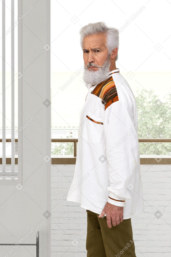 Old man standing on a balcony and looking at camera