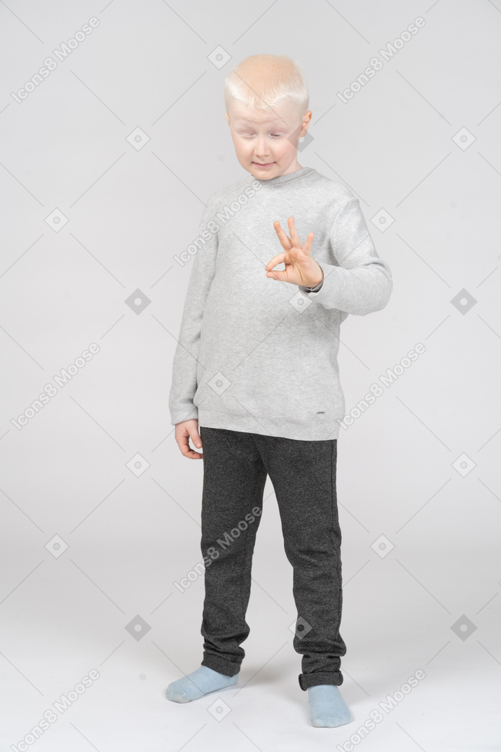 Front view of little boy showing ok sign