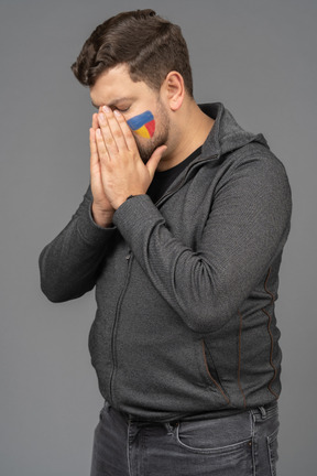 Three-quarter view of a withdrawn male football fan touching face