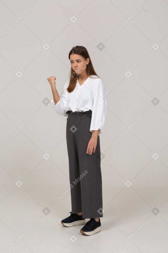 Three-quarter view of an angry young lady in office clothing clenching fist