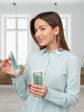 A woman in a blue shirt holding a stack of money