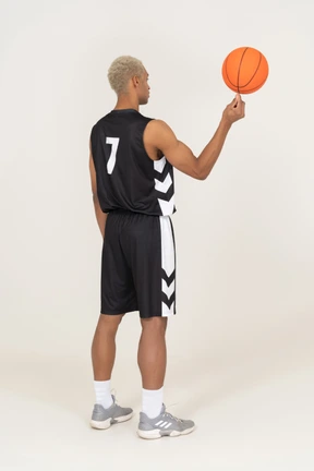 Three-quarter back view of a young male basketball player holding a ball