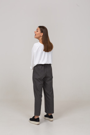 Vista posteriore di tre quarti di una giovane donna in abiti da ufficio in piedi con la bocca aperta