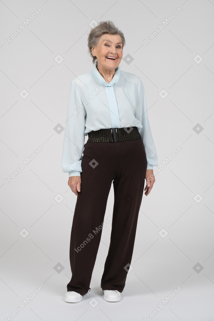 Vista frontal de una anciana sonriendo y guiñando un ojo con el ojo derecho