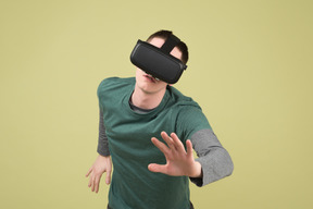 Young man in virtual reality headset reaching for something