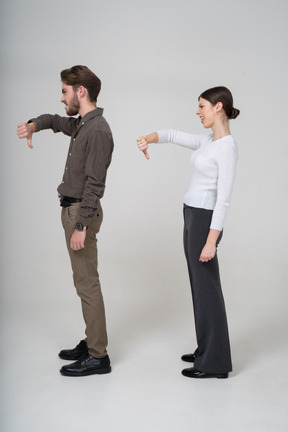 Side view of a young couple in office clothing showing thumb down