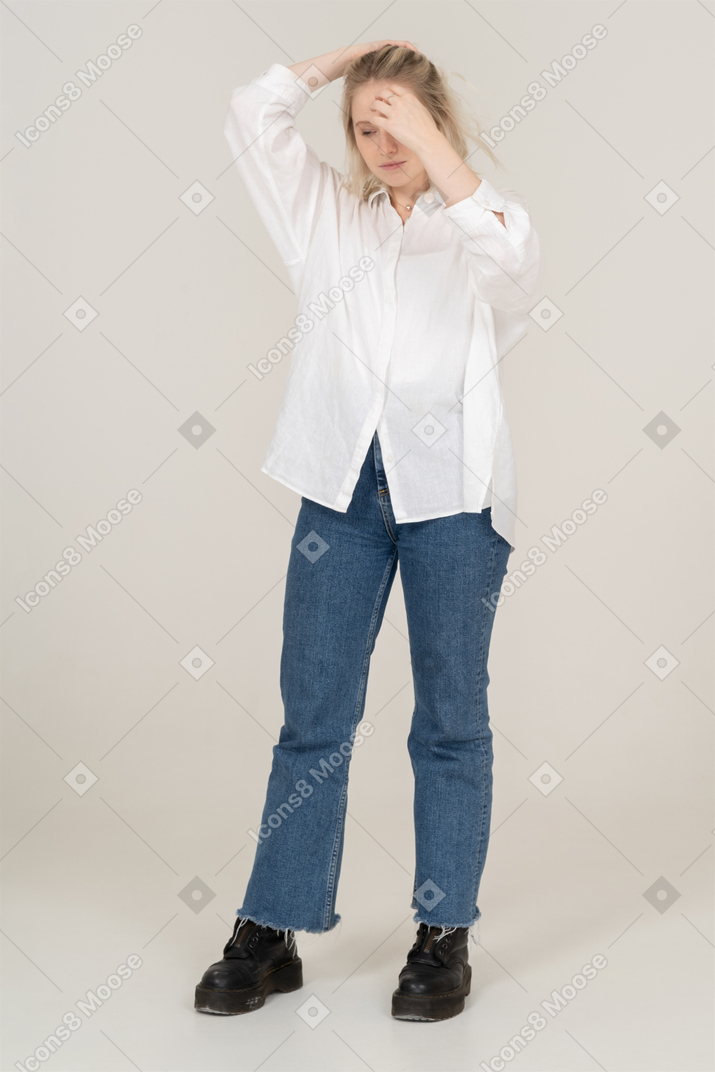 Front view of a young blonde female raising hands and touching her hair