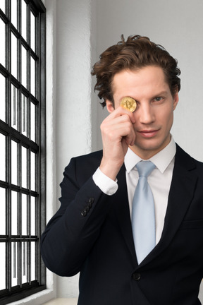 A man in a suit is holding a bitcoin in his hand