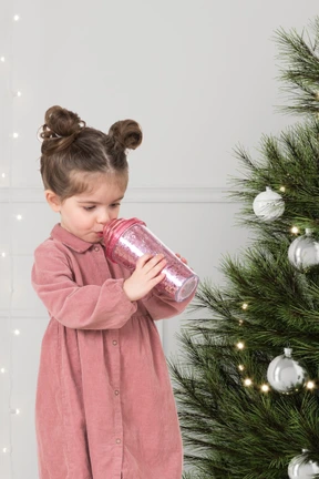 A little girl standing next to a christmas tree