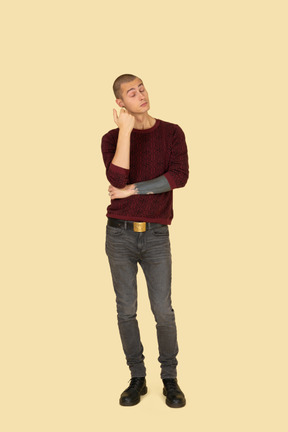 Front view of a thoughtful young man in red pullover raising hand