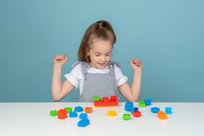 Petite fille assise derrière un bureau avec des blocs de construction