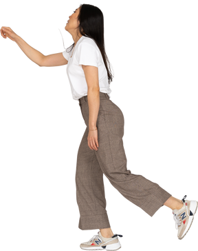 Vista lateral de una jovencita bailando en calzones y camiseta extendiendo su mano