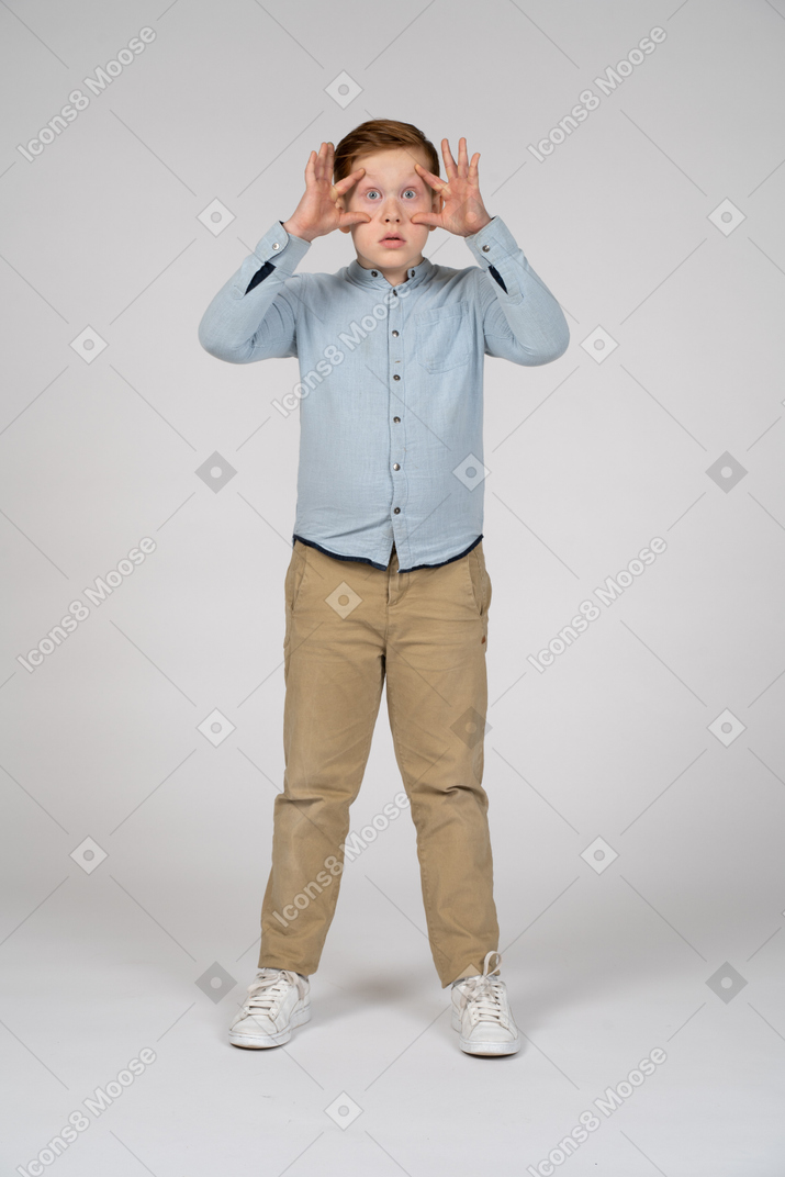Front view of an impressed boy looking through fingers