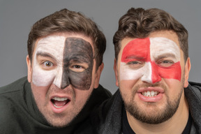 Front view of two male football fans with face art