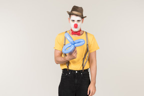 Sad looking male clown looking at balloon figure he's holding