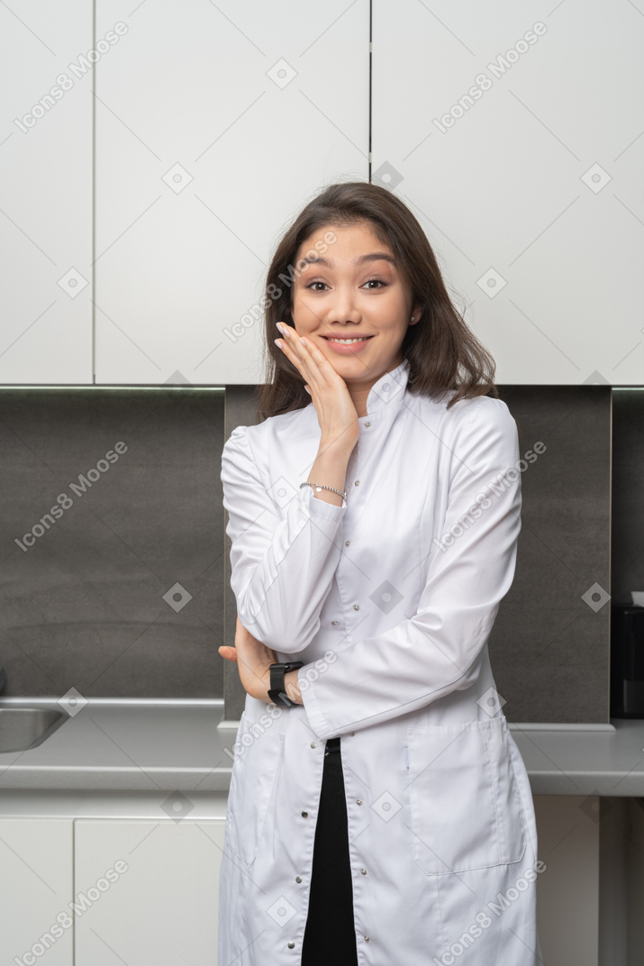 Vista frontal de uma enfermeira surpresa e sorridente tocando o rosto e olhando para a câmera