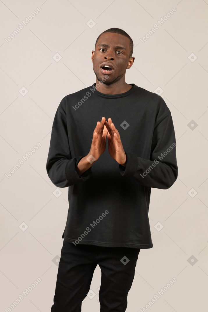 Shocked young man standing with hands together