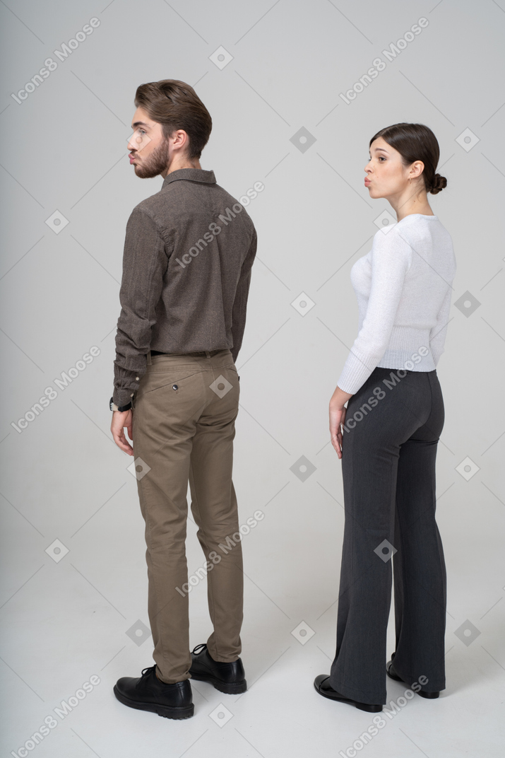 オフィスの服を着た若いふくれっ面のカップルの4分の3の背面図