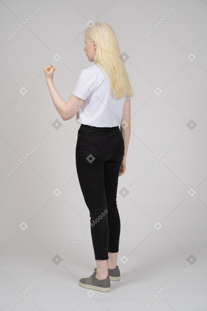 Vista traseira de uma jovem de pé com a mão em punho