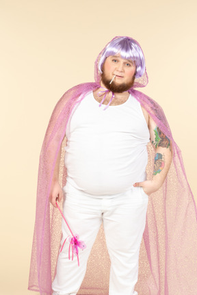 Young overweight man in violet fairy cape holding fairy wand