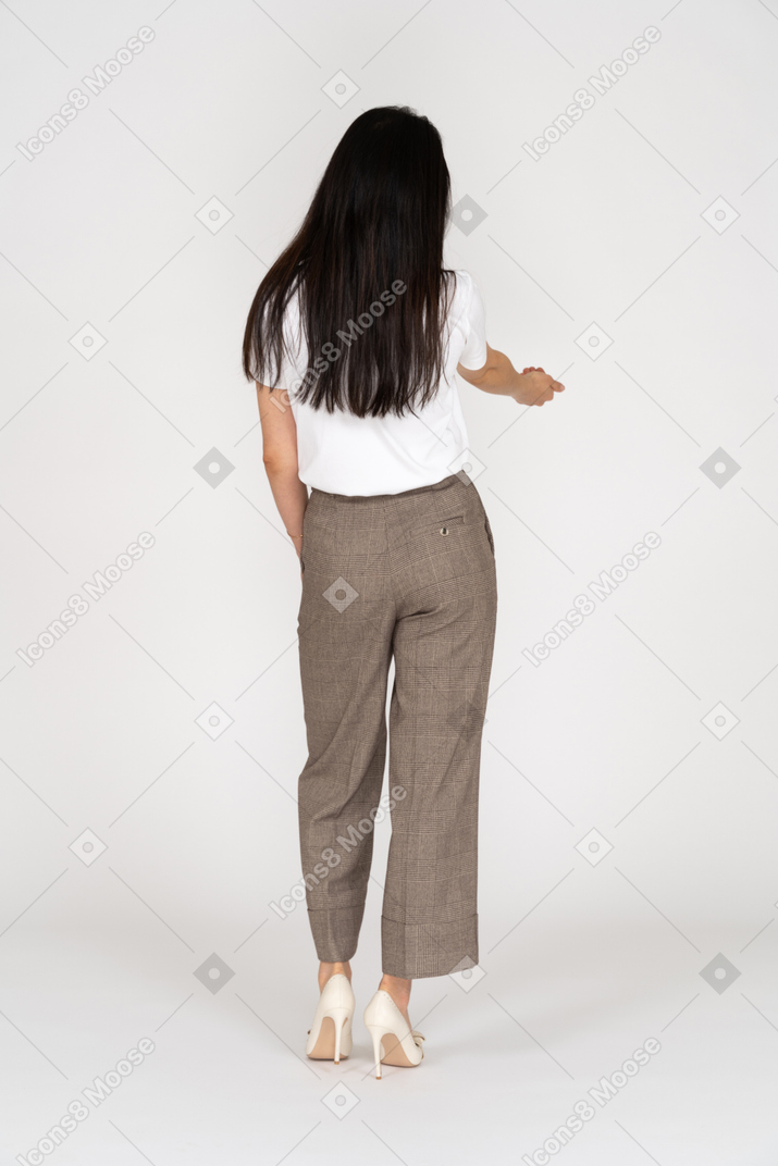 一位年轻的女士，穿着马裤和t恤伸出她的手的四分之三后视图