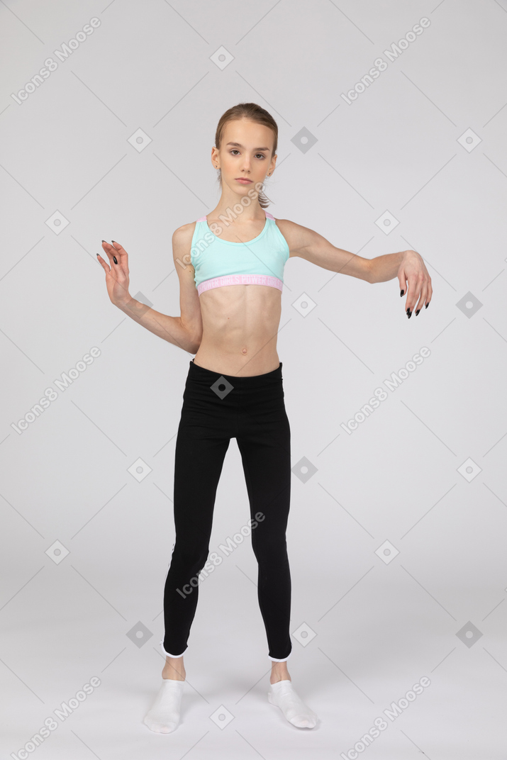 Front view of a teen girl in sportswear tilting shoulders and making waves