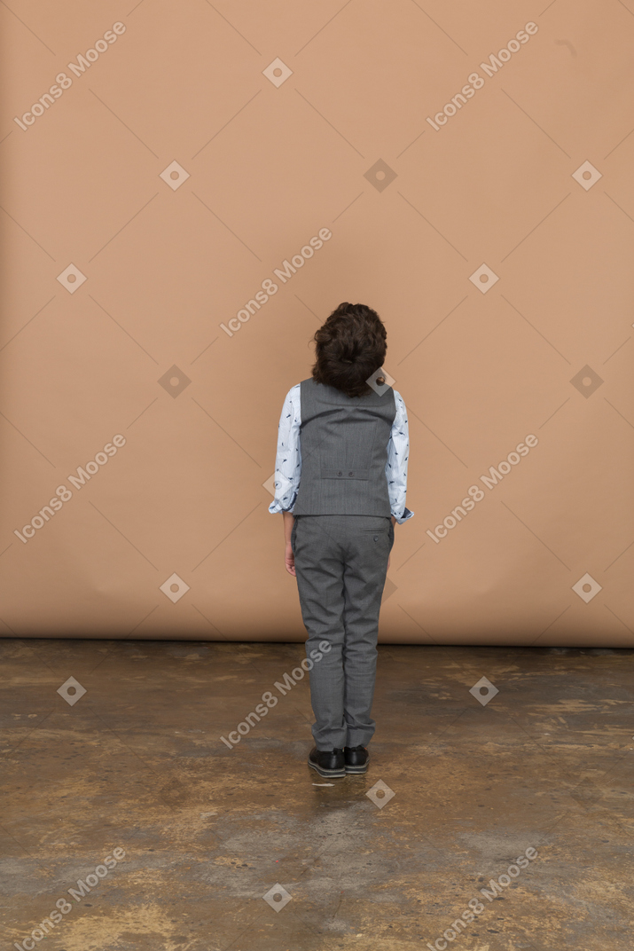 見上げるスーツを着た少年の背面図