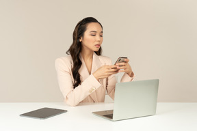 Empleado de oficina femenino asiático comprobando teléfono