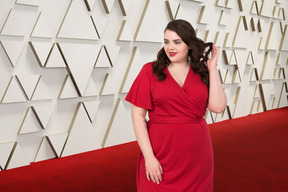 A woman in a red dress standing on a red carpet